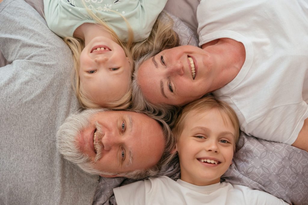 A joyful multigenerational family lying down and smiling together, displaying warmth and affection.